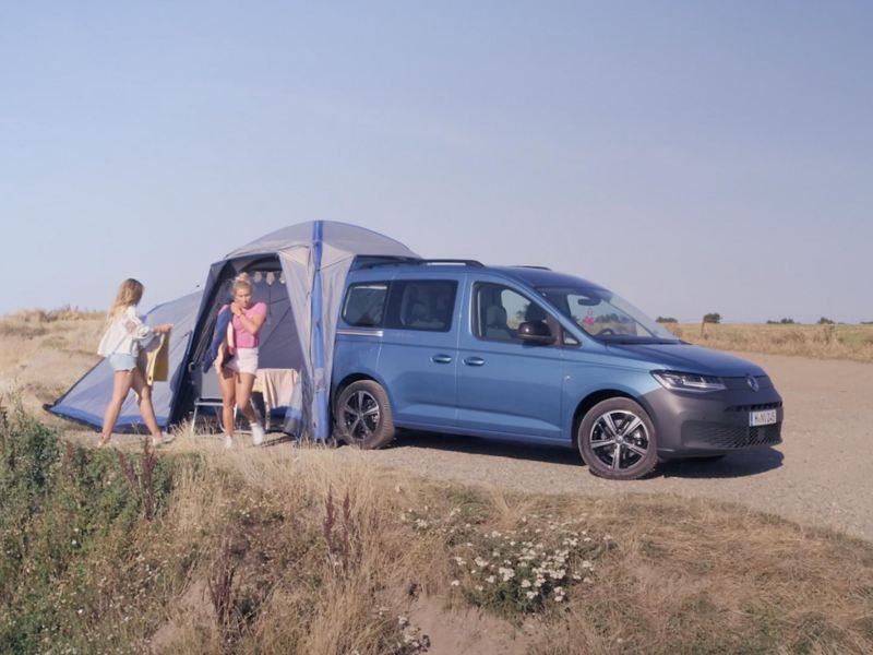 People exiting and entering tent of Volkswagen Caddy California.