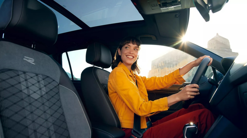 Vrouw zit achter het stuur van een Tiguan en lacht naar iemand buiten