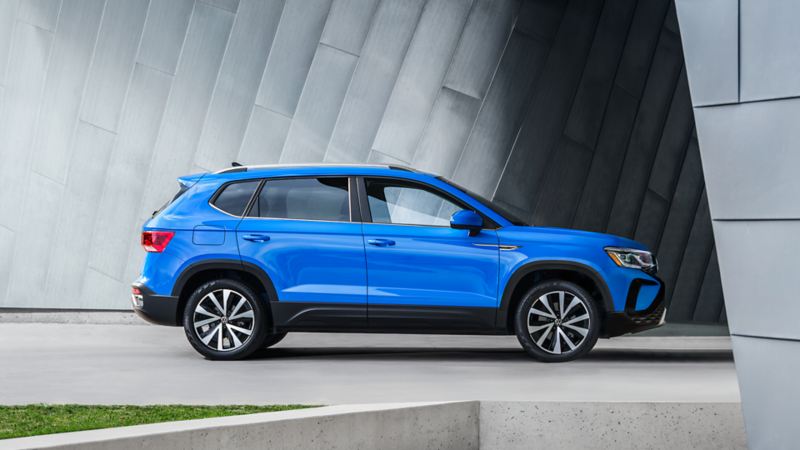 Un Volkswagen Taos 2023 bleu bleuet métallisé garé à côté d'un bâtiment futuriste.