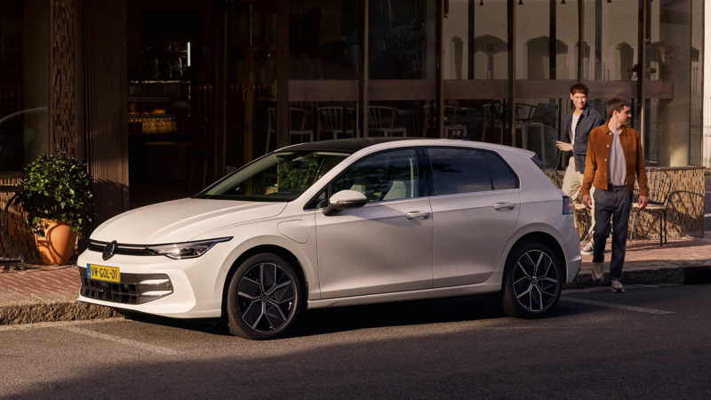 Witte Volkswagen Golf staat geparkeerd, twee mannen lopen achter de Golf