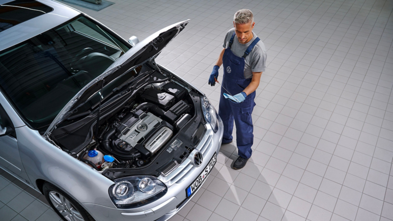 VW service employee checks the oil level of a VW Golf 5