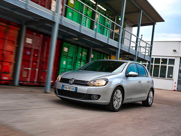 Una VW Golf 6 si muove all'interno di un'area di stoccaggio container.