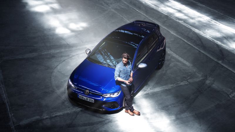 A man in casual clothing, leaning on a VW Golf R