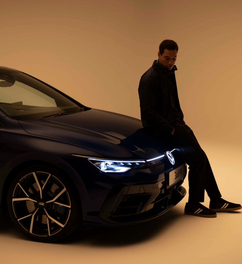 Man sitting on the front of Golf R with studio background