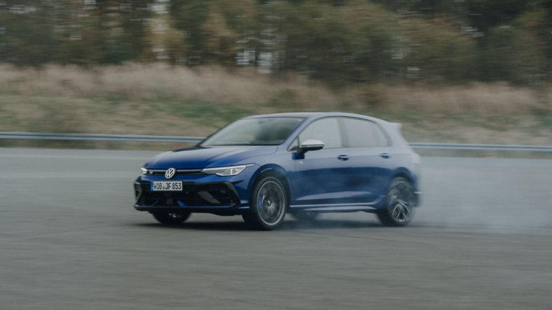 Ein Golf R in Lapiz Blue Metallic fährt über das Gelände einer Rennstrecke.