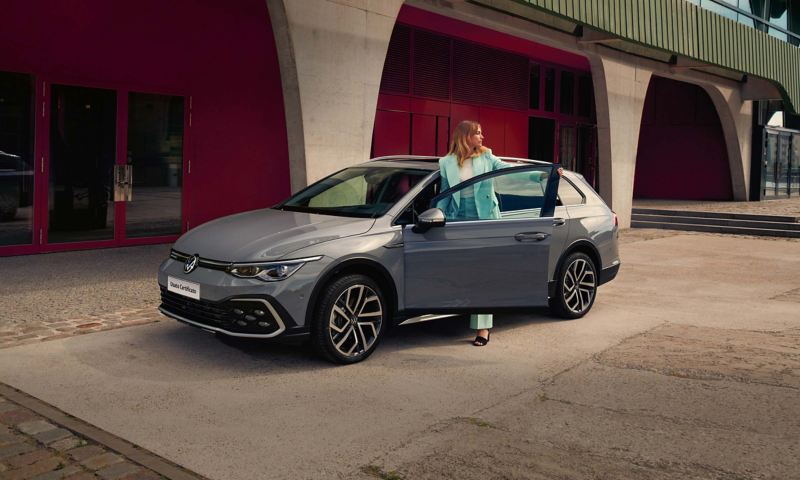 Una donna scende da VW Golf Alltrack in un parcheggio cittadino