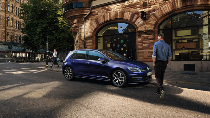 The Volkswagen Golf parked on a street - a man getting into the car