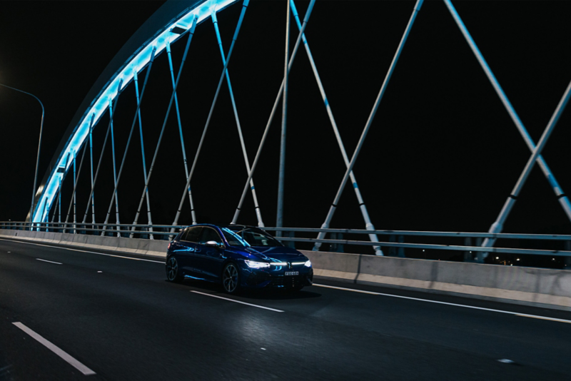VW Golf R driving over a bridge at night
