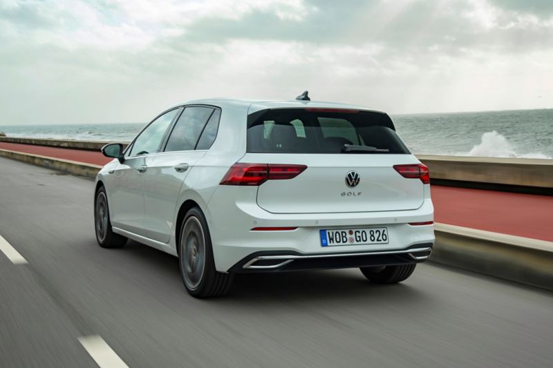 Vista posteriore di una Volkswagen Golf 8 eTSI mentre percorre una strada lungo mare.