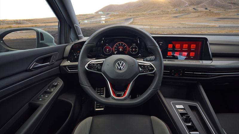 Golf GTI interior: steering wheel and a dashboard in front of mountains.