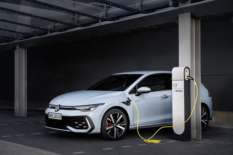 En vit VW Golf eHybrid står på laddning i en carport