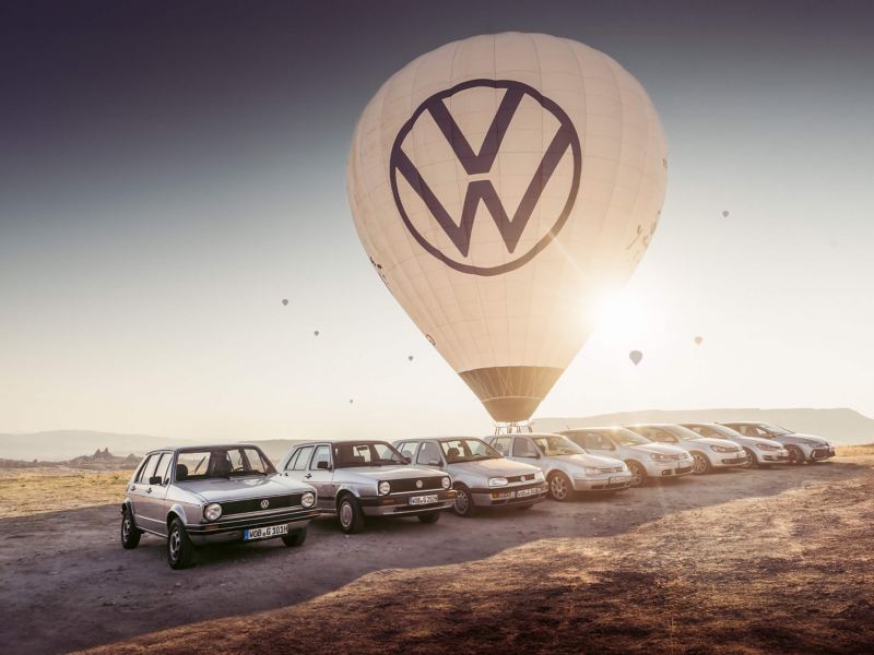 a hot air balloon with a VW logo and a line up of Golf models