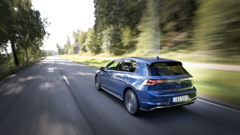 Mörkblå Volkswagen Golf kör på en landsväg med träd i omgivningen