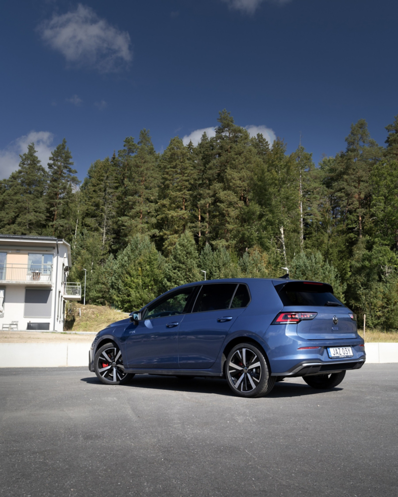 Mörkblå Volkswagen Golf står parkerad på en uppfart en sommardag
