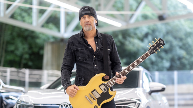 Der Gitarrist Freddy Scherer hält seine Gitarre in der Hand.