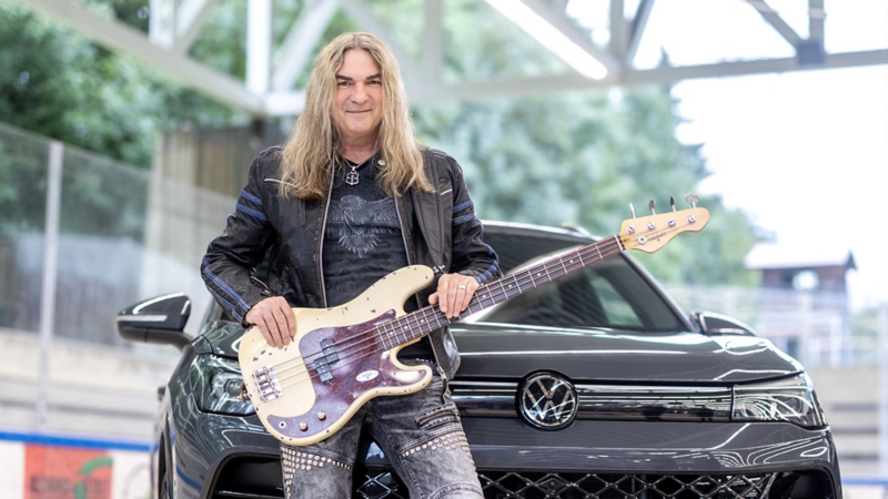 Marc Lynn steht vor seinem VW und hat eine Gitarre um.