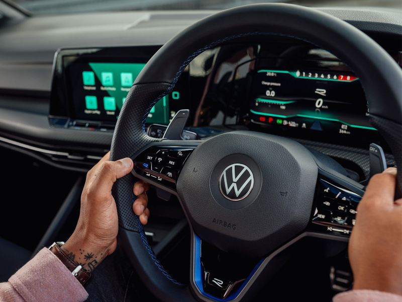 Person holding the steering wheel inside the Volkswagen Golf R