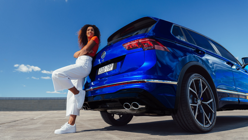Woman leaning against VW SUV in a carpark 