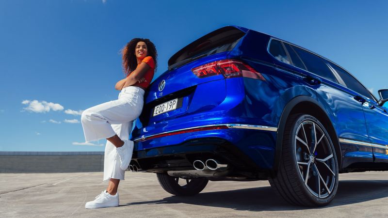 Close up of wheel of Volkswagen Tiguan R with model standing next to it.