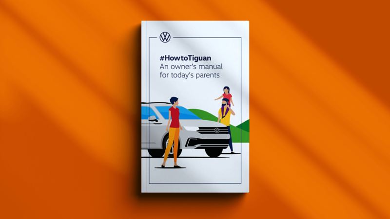 The How to Tiguan manual sitting closed on an orange background. The front cover of the manual depicts a cartoon of a family beside a 2022 Tiguan with the title ‘#HowtoTiguan An Owner’s manual for today’s parents’. 