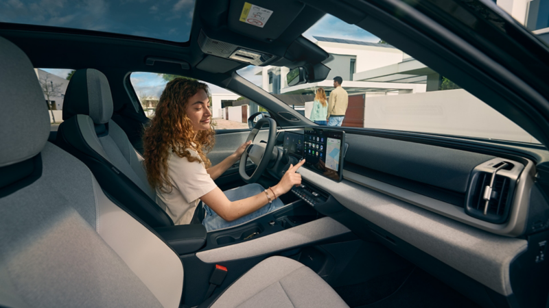 Une femme assise au volant d’un véhicule VW, vue de l’intérieur de l’habitacle.
