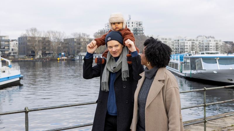 Jeniffer Mulinde Schmid geht mit ihrem Mann und ihrem Kind am Fluss entlang