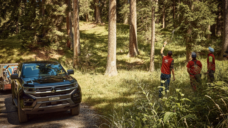VW Amarok im Wald parkiert und daneben drei Förster, die etwas besprechen