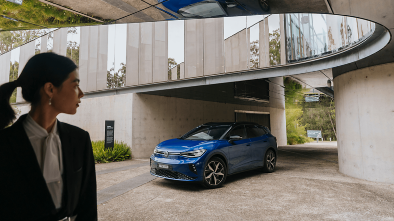 Woman looking back wistfully at her blue ID4. GTX