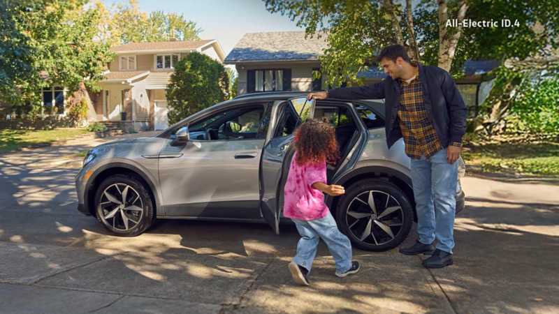 An Oryx White Pearl Volkswagen Jetta drives on a highway at dawn, with a blue and pink sky above a flat, brown landscape.