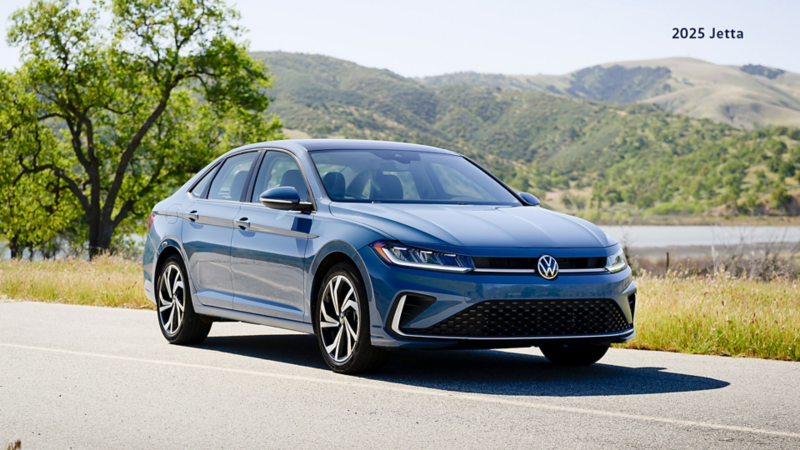 A Monterey Blue Pearl Volkswagen Jetta driving on a road.