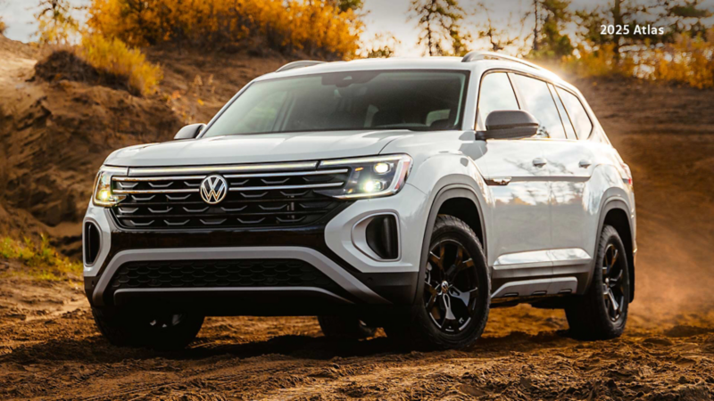 Pure White Volkswagen Atlas Peak Edition on a rugged dirt trail. The background shows trees and greenery under a bright sky.