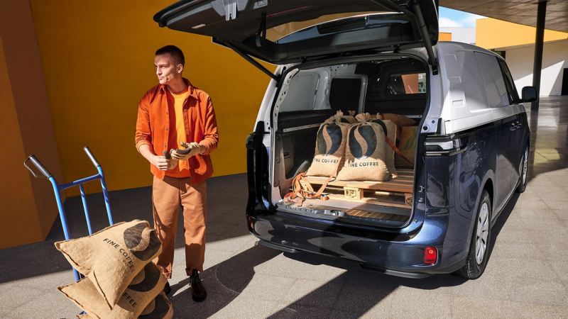 Το ID. Buzz Cargo της VW με ανοιχτό τον χώρο φόρτωσης. Ένας άνδρας φορτώνει εμπορεύματα.
