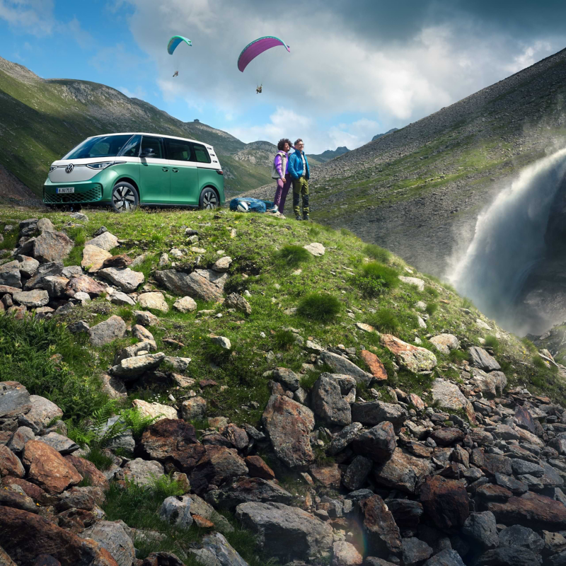 Der ID. Buzz Parkt an einer Bergschlucht. Ein Pärchen steht vor dem Abgrund und sieht auf die Landschaft.