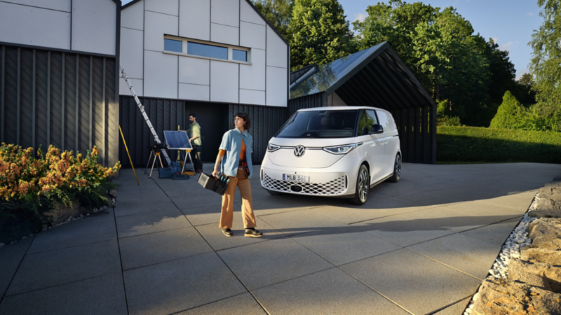 Två sollcellsinstallatörer tar en paus bredvid en vit VW ID. Buzz Cargo elskåpbil
