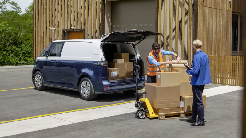 Två män kontrollerar lasten på en pall. I bakgrunden en VW ID. Buzz Cargo med öppen baklucka och halvfullt lastutrymme