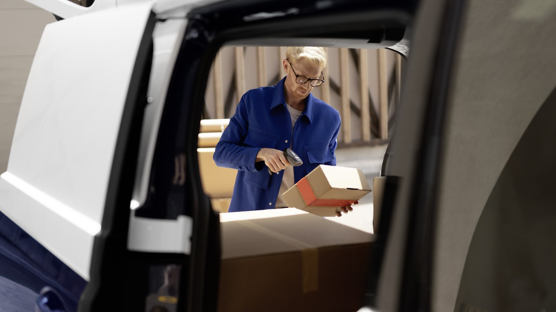 Man går igenom lasten i en VW ID. Buzz Cargo elbil med baklucka och skjutdörr öppna