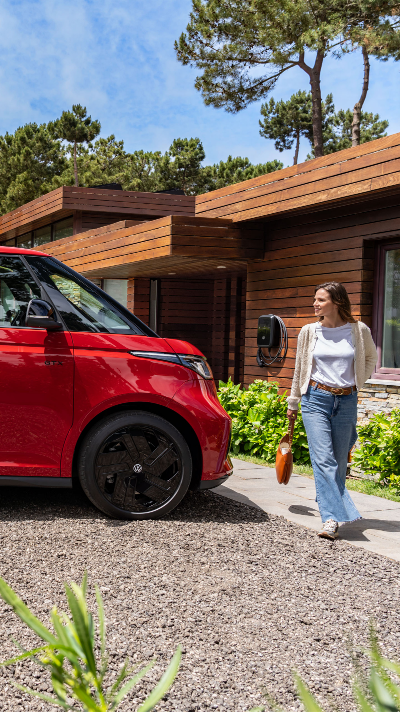 VW ID. Buzz GTX parkt vor einem Haus und eine Frau mit Handtasche geht vorbei.