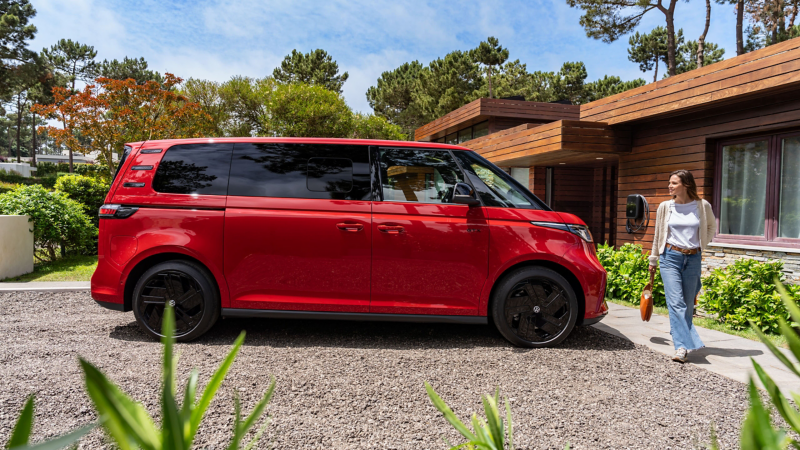 En kvinna går bredvid en röd VW ID Buzz GTX fyrhjulsdriven elbil