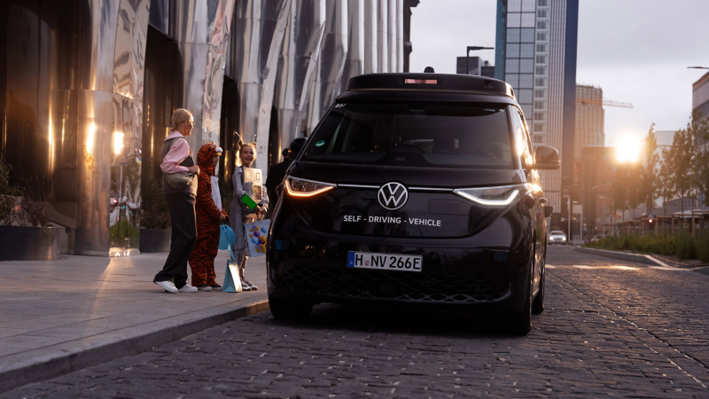 Der ID. Buzz parkt auf einer Straße neben 3 Personen.