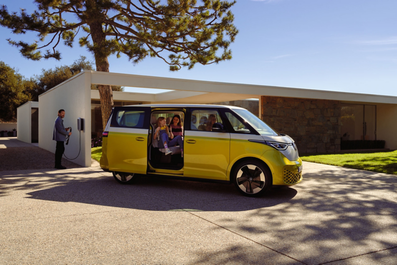 The ID. Buzz stands in front of a design bungalow with the side door open.