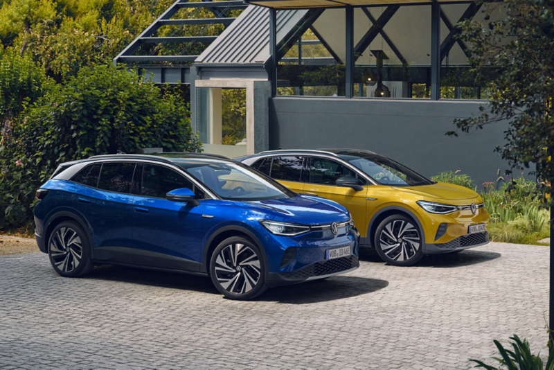 Dwa zaparkowane przed domem Volkswageny ID.4 wokół rośliny