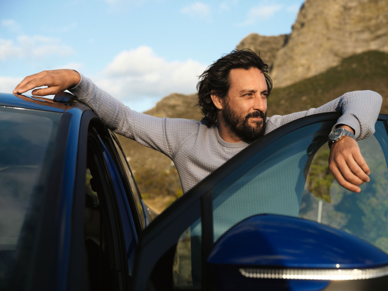 Man standing by the open door of a VW car