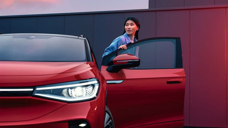 VW ID.5 GTX sarkanā krāsā, redzama priekšpuse, no automašīnas izkāpj sieviete