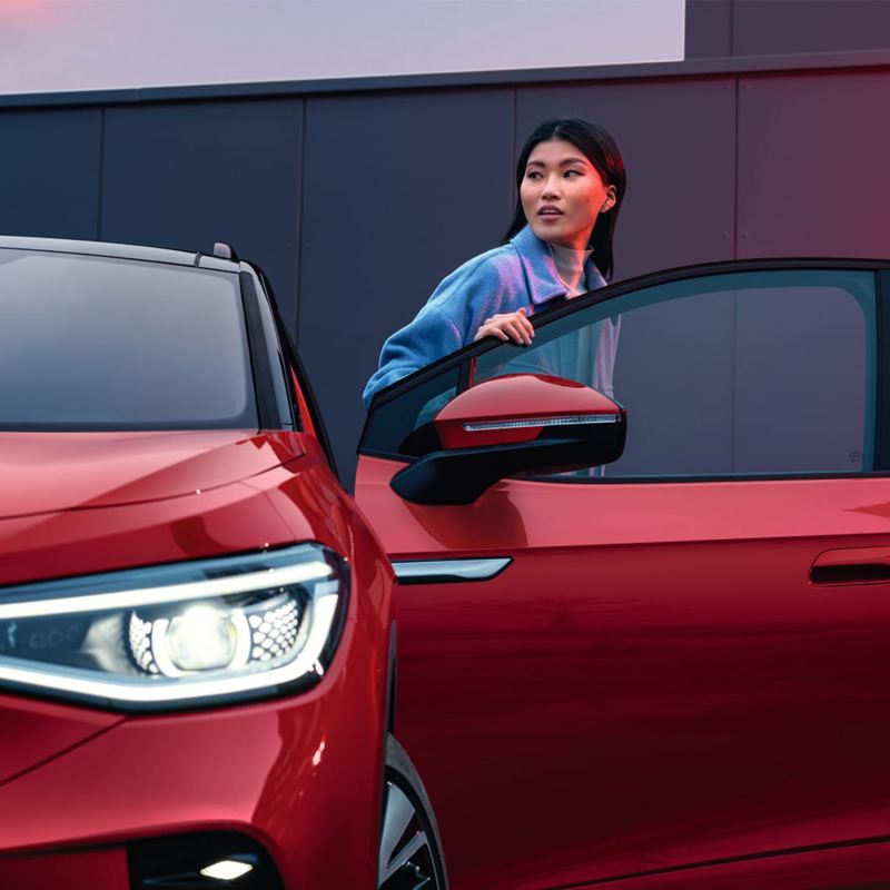 VW ID.5 GTX κόκκινου χρώματος, με ορατό το μπροστινό μέρος, από το οποίο εξέρχεται μια γυναίκα