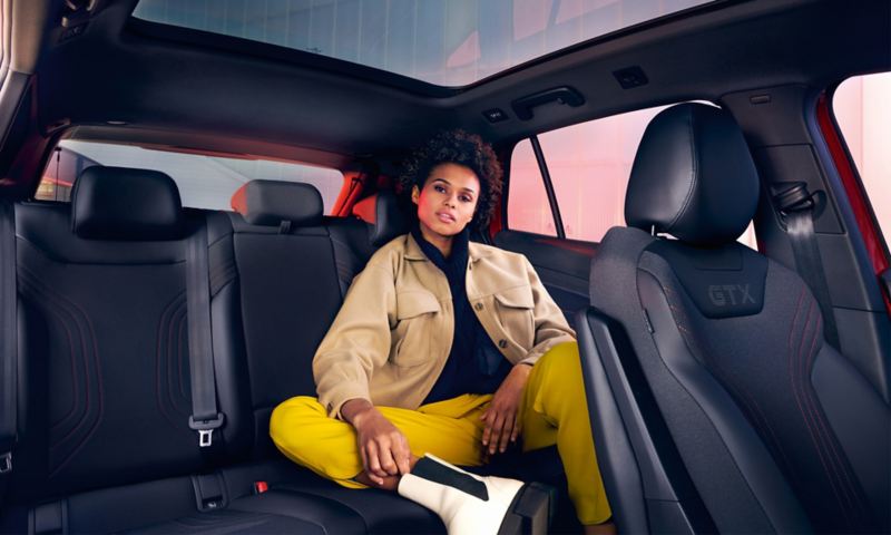VW ID.4 GTX intérieur. Une femme est assise à l'arrière, jambes repliées.