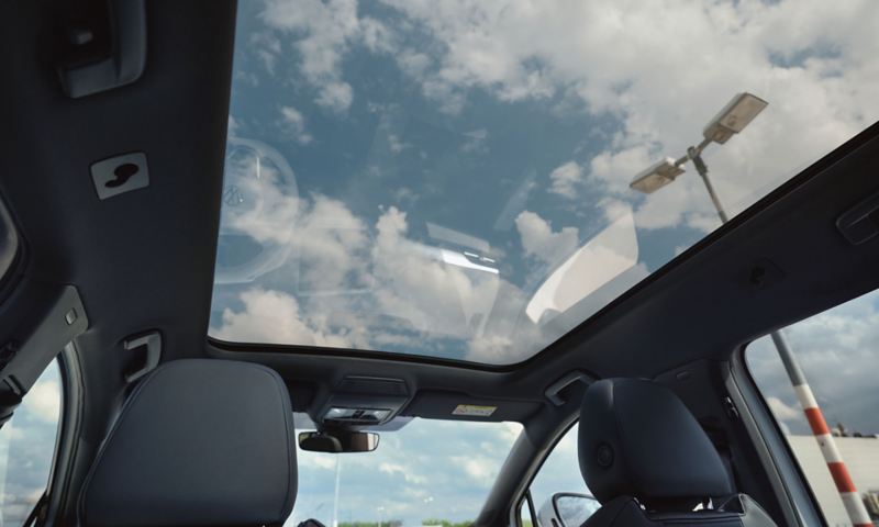 Innenansicht des VW ID.4. Blick aus dem großen Panoramadach auf einen blauen Himmel mit Wolken.