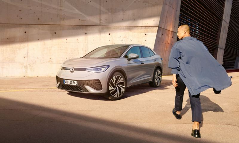 VW ID.5 in Grau steht auf einem Parkplatz. Ein Mann läuft darauf zu.
