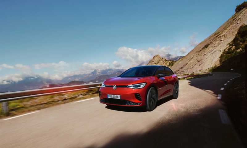 Red VW ID.5 GTX driving dynamically on a mountain road. View of front, wheels and side.