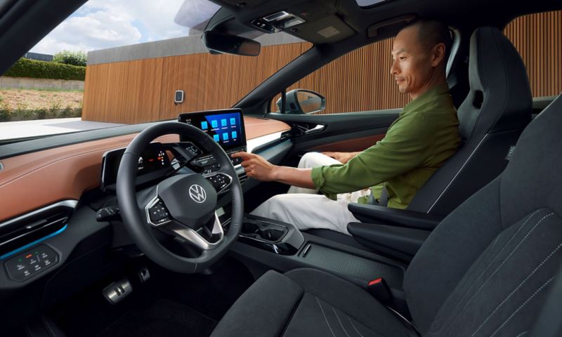 Vue depuis le côté conducteur d'un homme assis côté passager en train de se servir du système d'infotainment dans une Volkswagen ID.5