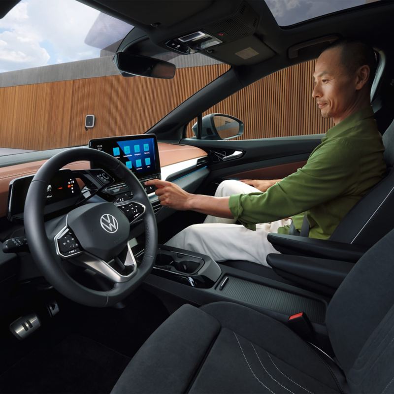 Blik in de bestuudersruimte van een VW ID.5. Man zittend op passagiersstoel en bedient infotainmentsysteem